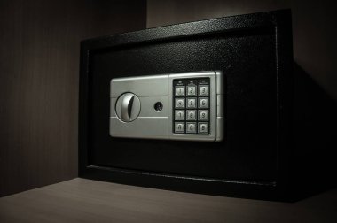 Karanlıkta rafta küçük, modern bir kasa. Küçük kasa, loş ışıkta kapanıyor. Seçici odak