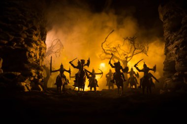 Süvari ve piyadelerle ortaçağ savaş sahnesi. Şekillerin siluetleri ayrı nesneler olarak, karanlık tonlu sisli arka planda ortaçağ şatosuyla savaşan savaşçılar arasında. Seçici odak