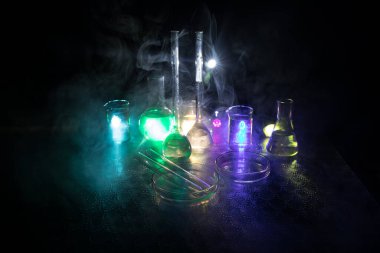 Eczane ve kimya teması. Araştırma laboratuarında çözeltisi olan cam deney şişesi. Bilim ve tıbbi geçmiş. Koyu renk arkaplan üzerinde laboratuvar test tüpleri, bilimsel araştırma ekipmanları konsepti