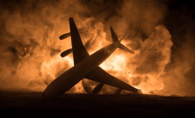 Uçak kazası. Düşen uçak yanıyor. Uçak yere çakıldı. Koyu renk arka planda oyuncaklarla süslenmiş. Uçak kazası konsepti. Seçici odak