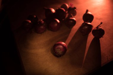 Sebze konsepti. Karanlıkta ahşap üzerine mor soğan. Seçici odaklanma. Renkli arkaplan.