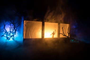 Sanat dekorasyonu. İçinde büyük pencereler ve zombiler olan eski bir ev. Penceredeki bulanık korkunç siluetler. Korku Cadılar Bayramı konsepti