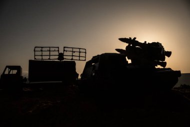 Yaratıcı sanat dekorasyonu. Gün batımında radar antenli mobil hava savunma aracı silueti. Roket fırlatıcı gökyüzüne nişan aldı ve saldırmaya hazır. Seçici odak