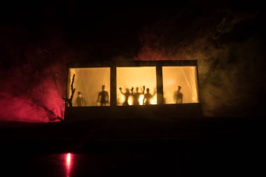Sanat dekorasyonu. İçinde büyük pencereler ve zombiler olan eski bir ev. Penceredeki bulanık korkunç siluetler. Korku Cadılar Bayramı konsepti
