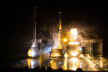 Eczane ve kimya teması. Araştırma laboratuarında çözeltisi olan cam deney şişesi. Bilim ve tıbbi geçmiş. Koyu renk arkaplan üzerinde laboratuvar test tüpleri, bilimsel araştırma ekipmanları konsepti