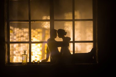 Dollhouse 'un penceresinden gece minyatür bir şehrin güzel manzarası. Pencerede romantik bir çift. El yapımı gerçekçi bebek eviyle sanat masası dekorasyonu. Seçici odak.