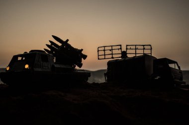 Yaratıcı sanat dekorasyonu. Gün batımında radar antenli mobil hava savunma aracı silueti. Roket fırlatıcı gökyüzüne nişan aldı ve saldırmaya hazır. Seçici odak