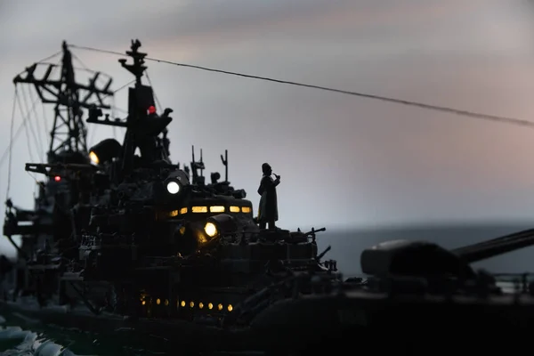 War concept. Night battle scene at sea. Dramatic toned clouds effect. Silhouette of the battle ship at sunset. Miniature creative table decoration. Selective focus