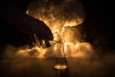 Eczane ve kimya teması. Araştırma laboratuarında çözeltisi olan cam deney şişesi. Bilim ve tıbbi geçmiş. Soyut patlama bulutu arkaplanındaki laboratuvar test tüpleri. Seçici odak