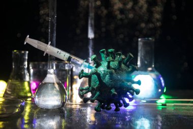Corona virüsü aşısı konsepti şırınga ve yeşil Corona virüsü romanı minyatür. Koronavirüsle mücadele aşısı. Sis ve arka ışıklandırmalı yaratıcı dekorasyon. Seçici odak
