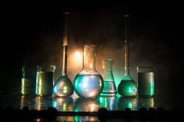 Eczane ve kimya teması. Araştırma laboratuarında çözeltisi olan cam deney şişesi. Bilim ve tıbbi geçmiş. Koyu renk arkaplan üzerinde laboratuvar test tüpleri, bilimsel araştırma ekipmanları konsepti