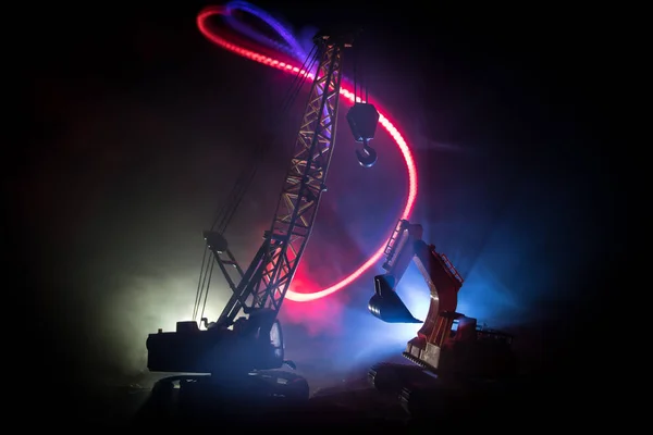 Abstract Industrial background with construction crane silhouette over amazing night sky with fog and backlight. Tower crane against the foggy sky at night. Industrial skyline. Selective focus