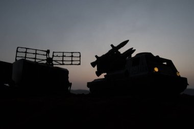 Yaratıcı sanat dekorasyonu. Gün batımında radar antenli mobil hava savunma aracı silueti. Roket fırlatıcı gökyüzüne nişan aldı ve saldırmaya hazır. Seçici odak