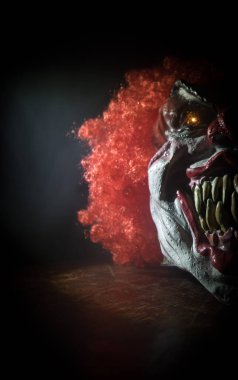 Tahta masadaki Ürkütücü Palyaço kafası. Karanlık sisli arka planda gülümseyen şeytani palyaço. Cadılar Bayramı konsepti Seçici odak