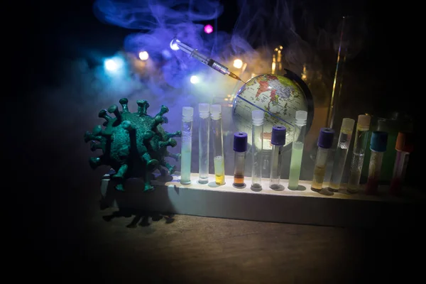 Corona virus Vaccine concept with syringe and green Corona virus novel miniature. Vaccine Concept of fight against coronavirus. Creative decoration with fog and backlight. Selective focus