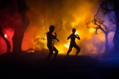 Yanan Orman 'da karate sporcuları gece dövüşü sahnesi. Karakter karatesi. Sanatçı figürü dekorasyonu. Spor konsepti. Işıkla süslenmiş sisli bir arka plan. Seçici odak