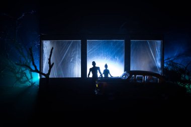 Sanat dekorasyonu. İçinde büyük pencereler ve zombiler olan eski bir ev. Penceredeki bulanık korkunç siluetler. Korku Cadılar Bayramı konsepti