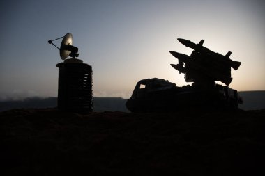 Yaratıcı sanat dekorasyonu. Gün batımında radar antenli mobil hava savunma aracı silueti. Roket fırlatıcı gökyüzüne nişan aldı ve saldırmaya hazır. Seçici odak