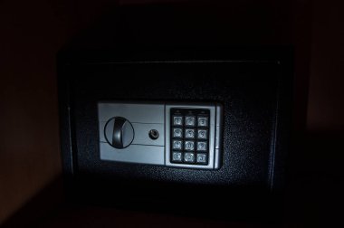 Karanlıkta rafta küçük, modern bir kasa. Küçük kasa, loş ışıkta kapanıyor. Seçici odak