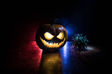 Corona virüsü küresel pandemik konsepti sırasında Cadılar Bayramı. Karanlıkta parlayan balkabakları ve Covid romanı tematik ürkütücü süslemelerle. Cadılar Bayramı balkabağı sisli arka planda. Seçici odak