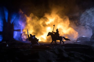 Süvari ve piyadelerle ortaçağ savaş sahnesi. Şekillerin siluetleri ayrı nesneler olarak, karanlık tonlu sisli arka planda ortaçağ şatosuyla savaşan savaşçılar arasında. Seçici odak