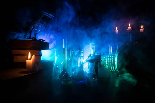 ウィザーズ デスク ホラーハロウィンのコンセプト 本やろうそくと木製のテーブルの上のボトルの魔法のポーション 暗いトーン霧の背景に異なる要素を持つハロウィーンの静物の背景 選択的焦点 — ストック写真