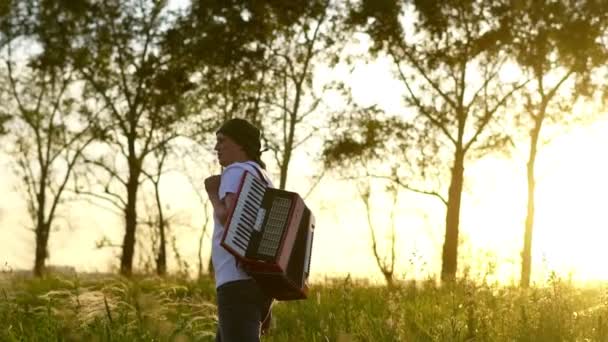 Um homem caminha num campo ao pôr-do-sol — Vídeo de Stock