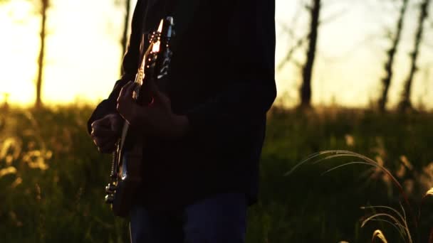 Egy zenész gitározik naplementekor — Stock videók