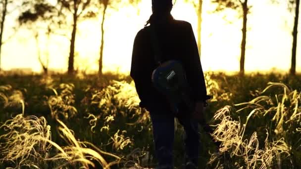 Un hombre camina en un campo al atardecer — Vídeos de Stock