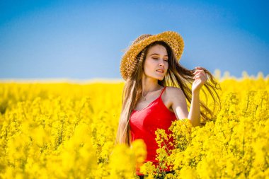 Kolza tohumu içindeki kızın bahar portresi. Örnek bir kadının kanola tarlasında güneşlendiği ve sarı çiçeklerin açtığı kırsal bir yer. Mutluluk, mutluluk ve özgürlük kavramı.