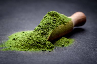 Yeşil çay, matcha. Toz arpa tozu ya da tahtadan kepçe üzerine buğday tozu. Detoks süper gıda konsepti.