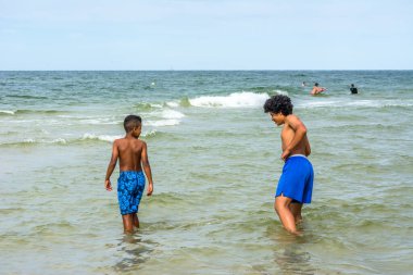 LEBA, POLAND - 31 HAZİRAN 2016: Baltık Denizi üzerinde yaz tatilinde, denizde oynayan siyahi çocuklar