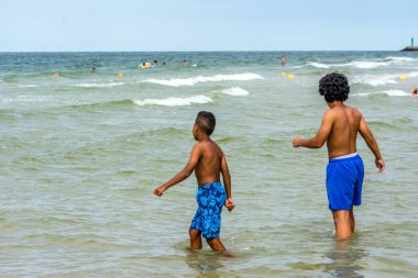 LEBA, POLAND - 31 HAZİRAN 2016: Baltık Denizi üzerinde yaz tatilinde, denizde oynayan siyahi çocuklar