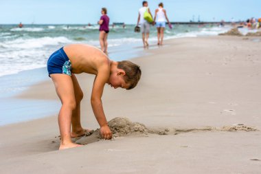 LEBA, POLAND - 31 Temmuz 2016: Baltık Denizi üzerinde kumsalda oynayan genç çocuk