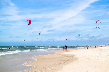 LEBA, POLAND - 09 Temmuz 2016: Polonya 'daki Leba plajında uçurtmacılar. Polonya deniz kıyıları uçurtma uçurmak gibi aşırı su sporları için popüler bir yerdir..