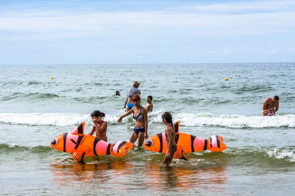 LEBA, POLAND - 31 Temmuz 2016: Annesine bakan iki küçük kız deniz suyunda eğleniyor, turistler yaz tatilinde plajda eğleniyor