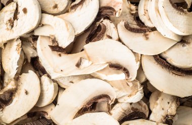 Background with mushrooms champignon sliced, vegetarian food close-up.