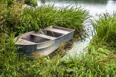 Kıyıdaki gölde sazlıkların arasında balık tutmak için bir tekne. Açık hava düğün teması. Tatil, tatil, eğlence ve ilişki teması.