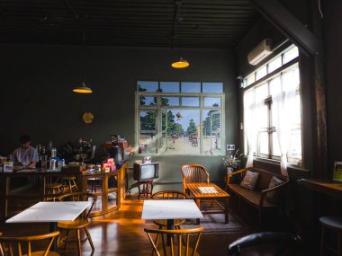 Bangkok 'ta ahşap mobilyaları, güzel bir duvar resmi ve pencereden süzülen yumuşak güneş ışığıyla seçkin bir kafe.