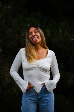 Siyah saçlı Latin bir kızın portresi. Ormanın ortasında parlak gözlü sıradan bir kot pantolon giyiyor.