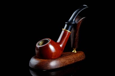 Siyah arka plandaki ahşap tutacakta tütün piposu içmek.