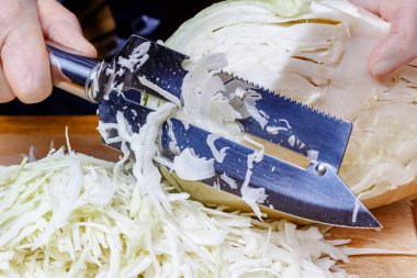 Paslanmaz çelik bıçakla taze beyaz lahana doğrayan kadın.