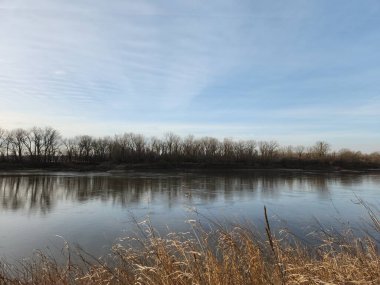 Gün doğumunda sakin bir nehir. Yumuşak ışık ve kışın gökyüzü yansımaları.