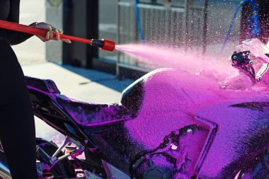 Yüksek basınçlı pembe köpük oto yıkamada motosikleti yıkar. Seçici odak.