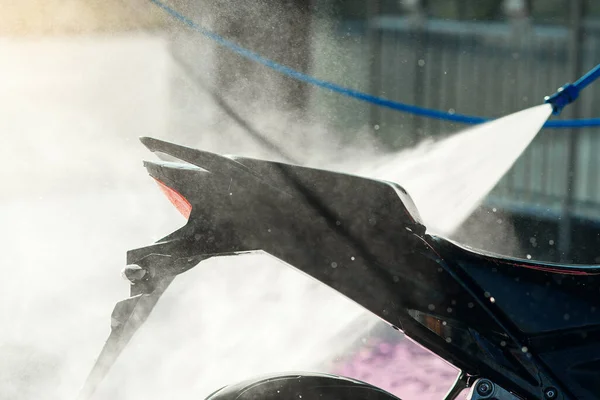 Nahaufnahme Hochdruckwasser wäscht ein Motorrad in einer Selbstbedienungswaschanlage. Selektiver Fokus. — Stockfoto