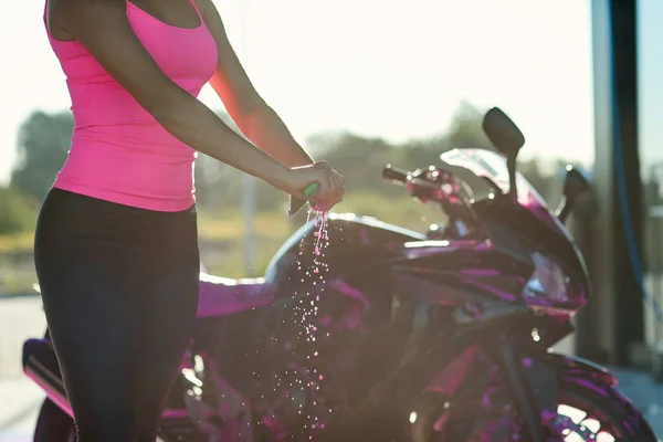 Fechar as mãos das mulheres espremer a umidade fora do pano enquanto limpa motocicleta esporte em auto-serviço lavagem de carro. — Fotografia de Stock