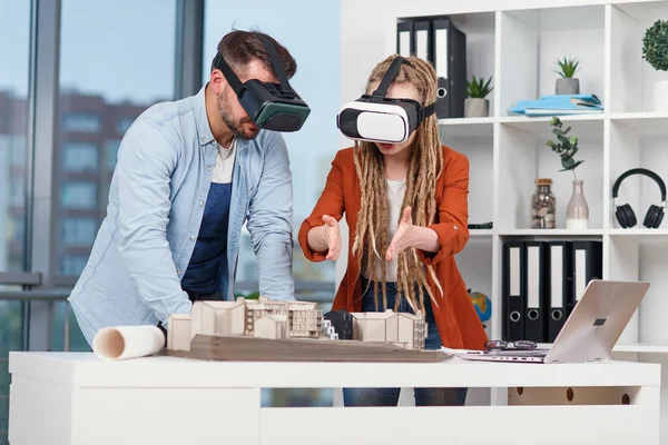 Grupo de jovens arquitetos na VR óculos de trabalho com maquete de uma casa no escritório moderno. — Fotografia de Stock
