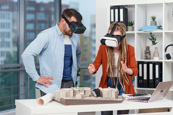Casal de arquitetos ou engenheiros em óculos VR trabalhando com maquete de futura área residencial no escritório moderno. — Fotografia de Stock