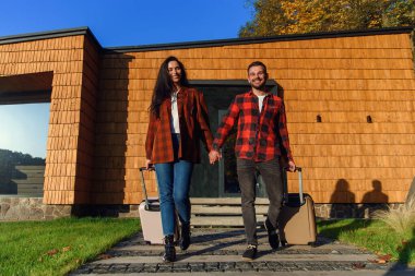 Bavulları olan beyaz, güzel bir çift, ortak tatil için evden ayrılıyorlar. Mutlu aile kavramı.