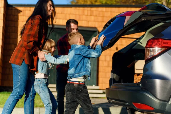 Uma família feliz carrega bagagem no porta-malas de um carro quando vai de férias em família. — Fotografia de Stock